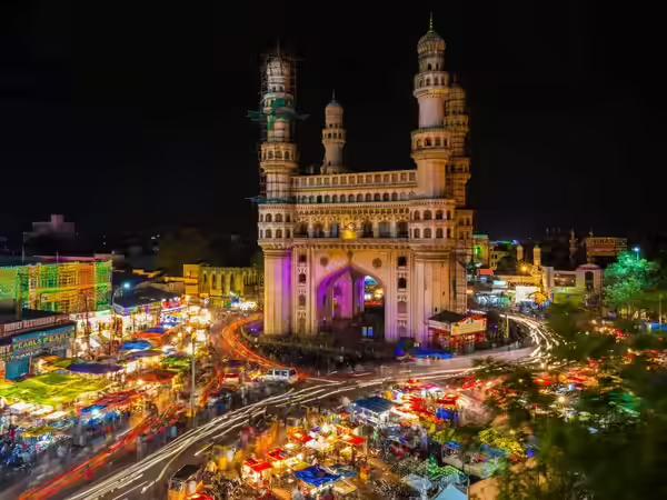 Charminar illuminated at night, with the surrounding market lit up below