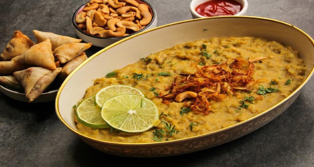 A plate of Hyderabadi haleem garnished with fried onions and lime